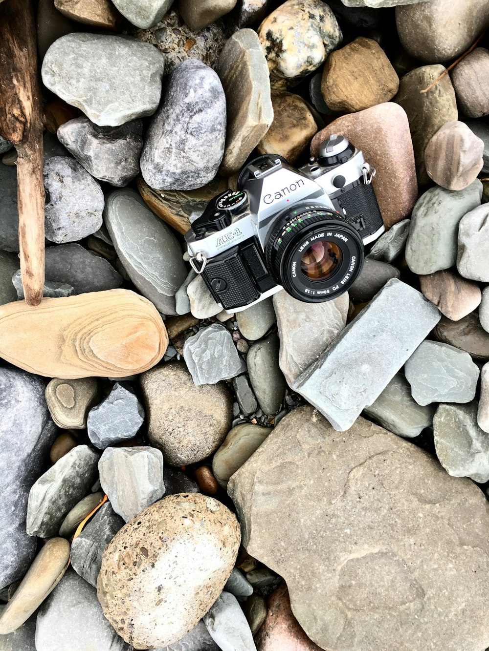 black and silver dslr camera on gray and brown stones