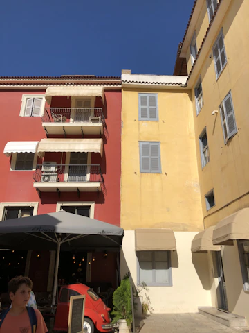A sunny travel scene with a blue sky and yellow accents, showing a traveler with a backpack exploring a vibrant city street.