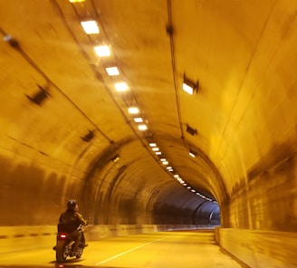 man in black jacket and black pants walking on tunnel