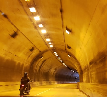 man in black jacket and black pants walking on tunnel