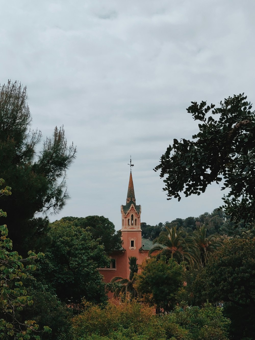 brown concrete building surrounded by green trees under gray sky