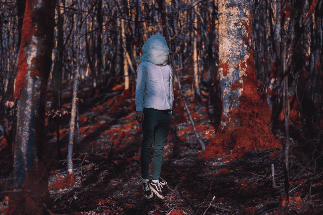 woman in gray hoodie and black pants standing on forest during daytime