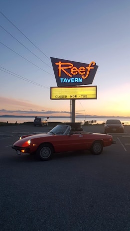 Red Hot Ed’s iconic 1979 red Corvette parked outside a cozy roadside diner at sunset.
