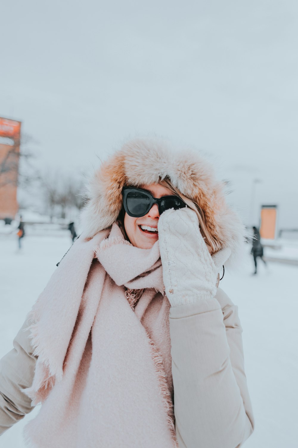 a woman wearing sunglasses and a pink coat in the snow