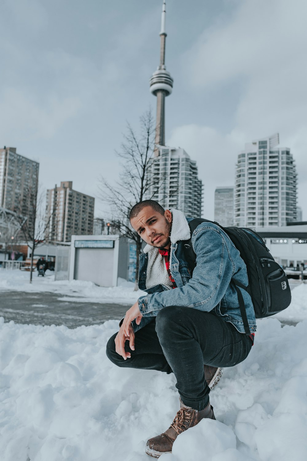 a man kneeling in the snow with a backpack