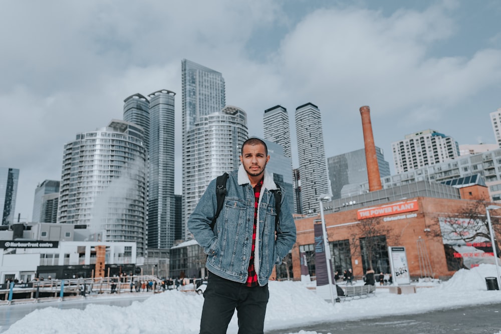 a man standing in the snow in front of a city