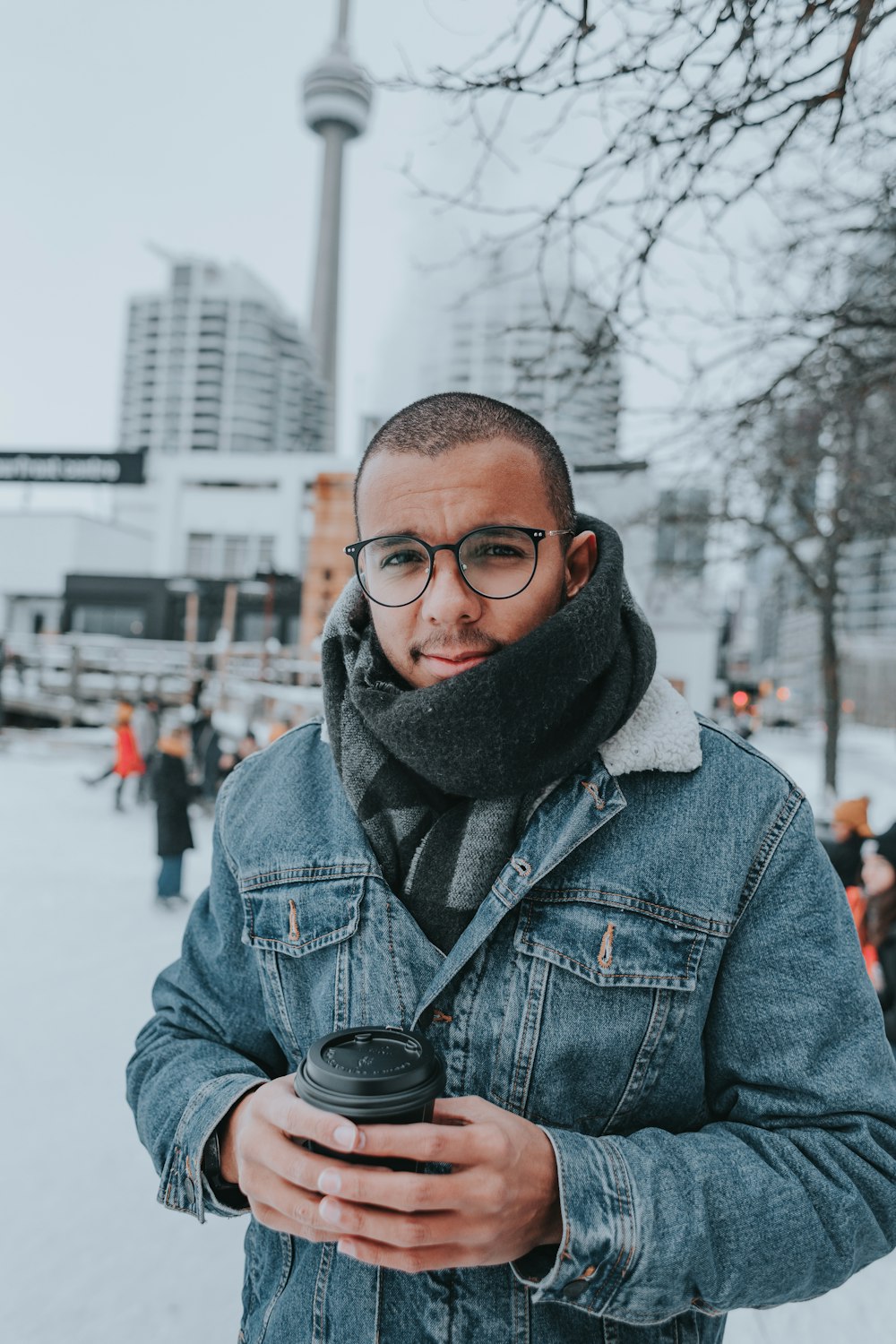 Un homme portant des lunettes et un foulard tenant un appareil photo