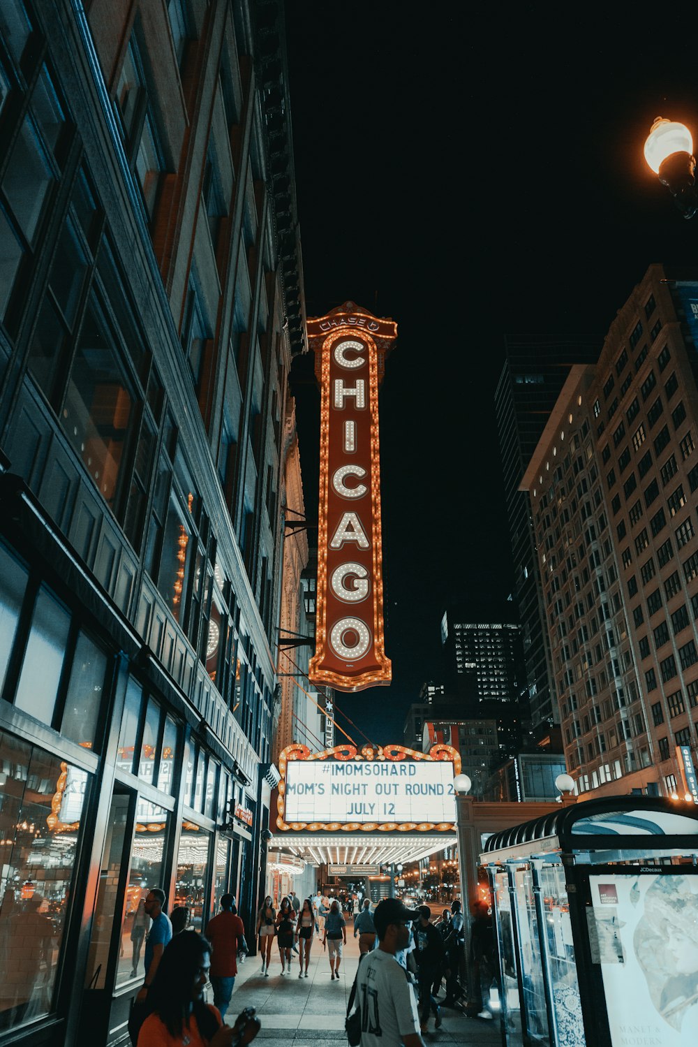 people walking on a sidewalk in front of a theater