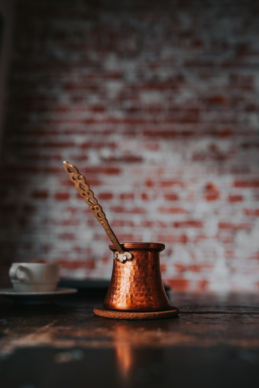 uma colher de pau em um copo de cobre em uma mesa