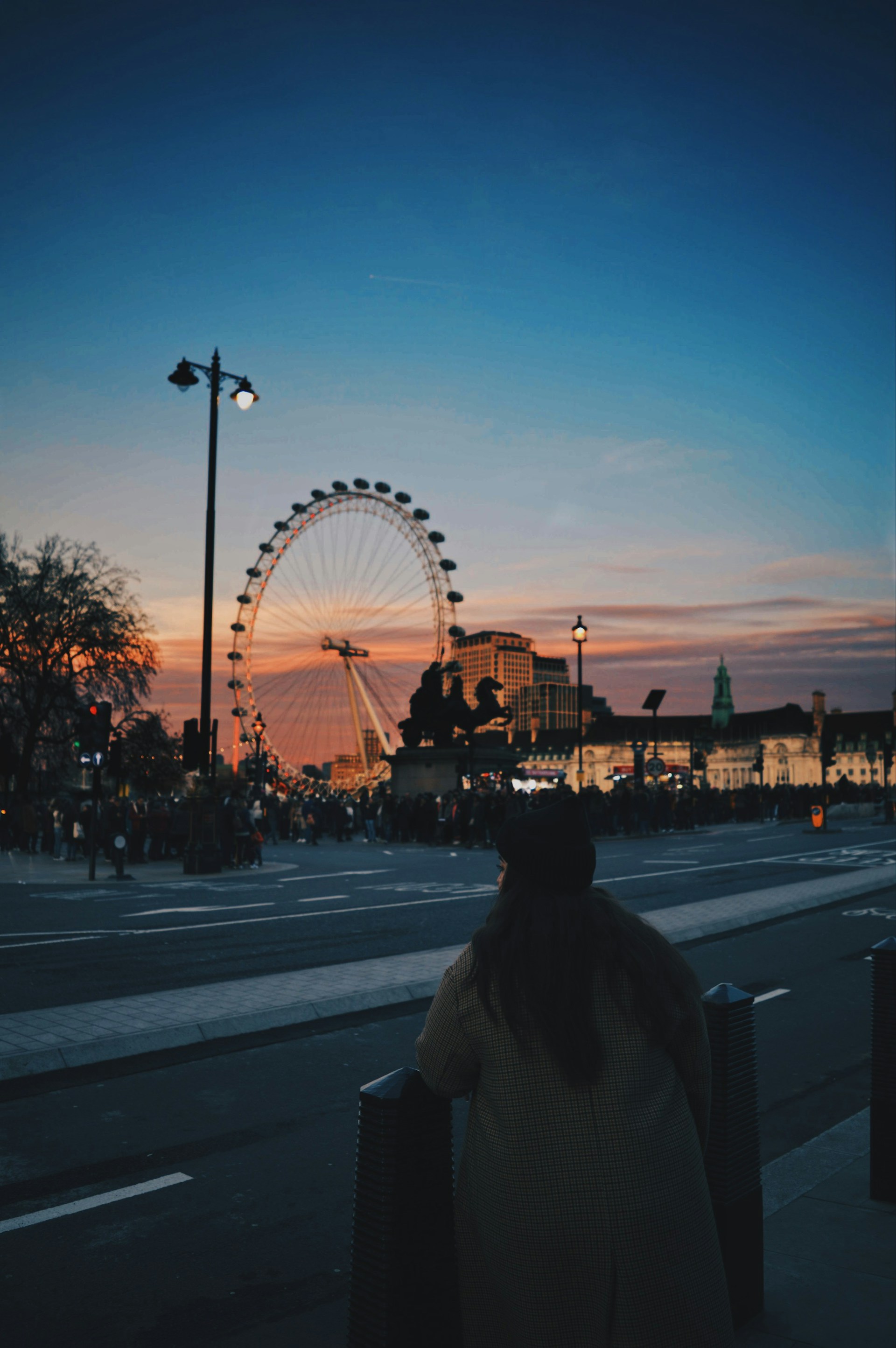 person in gray jacket standing on sidewalk during night time