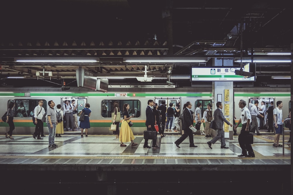 um grupo de pessoas caminhando em uma plataforma ao lado de um trem
