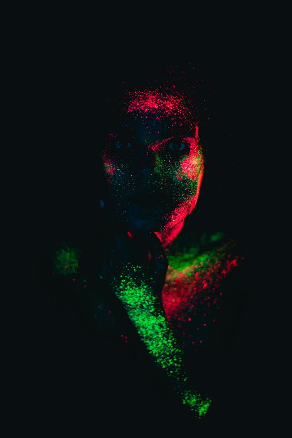 Un uomo in una stanza buia con polvere colorata sul viso