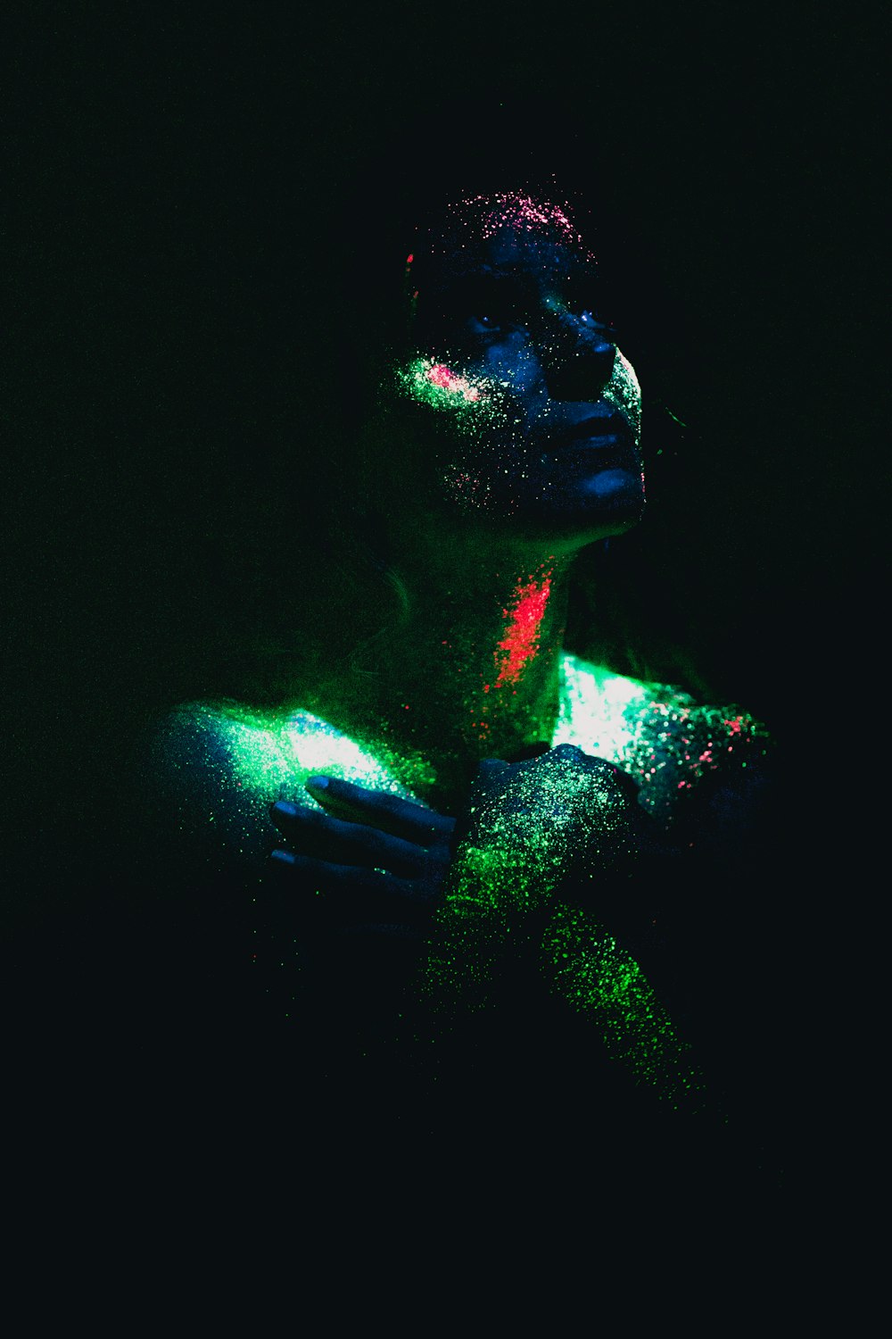 a woman covered in colored powder in the dark