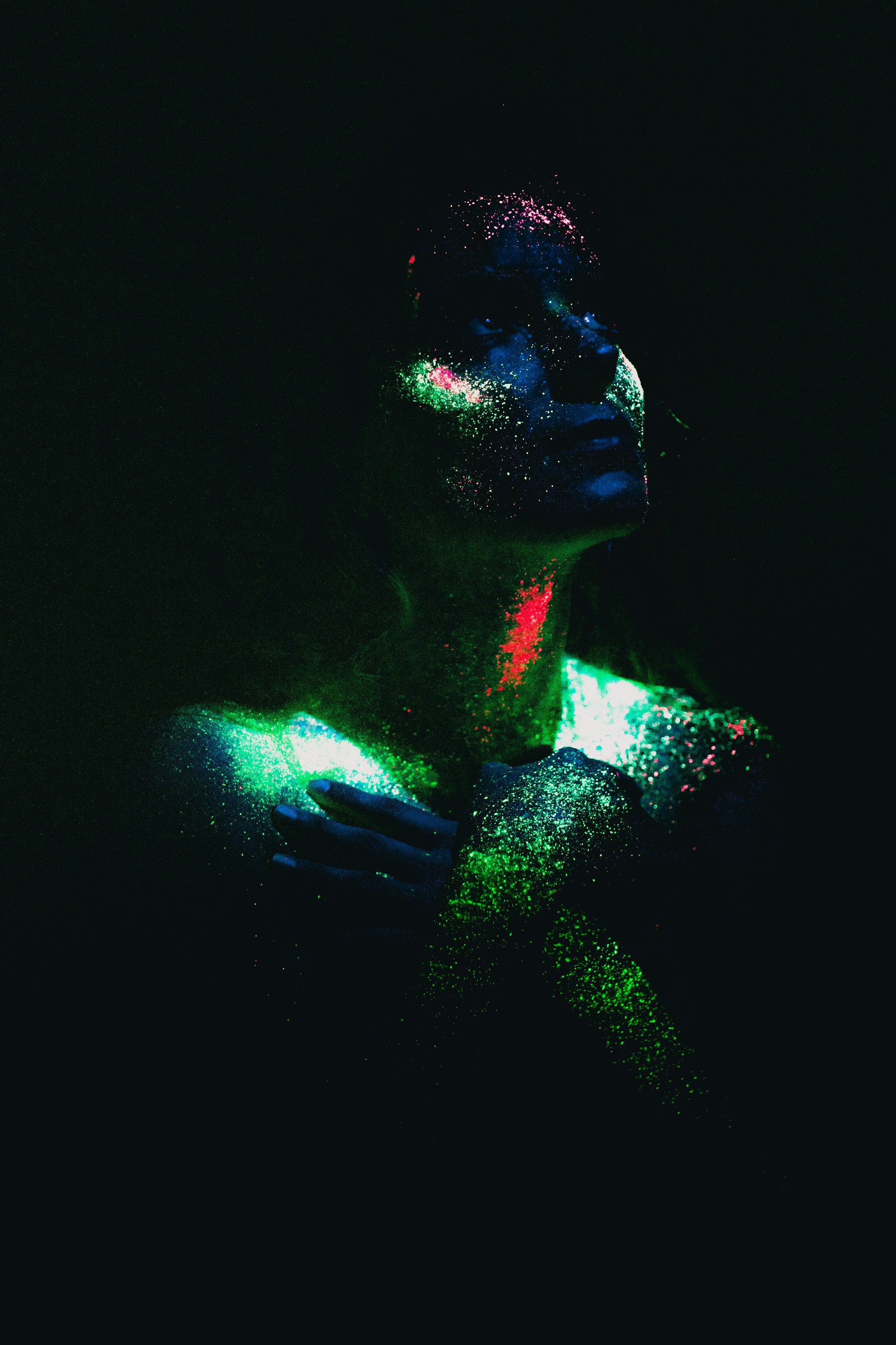 a woman covered in colored powder in the dark