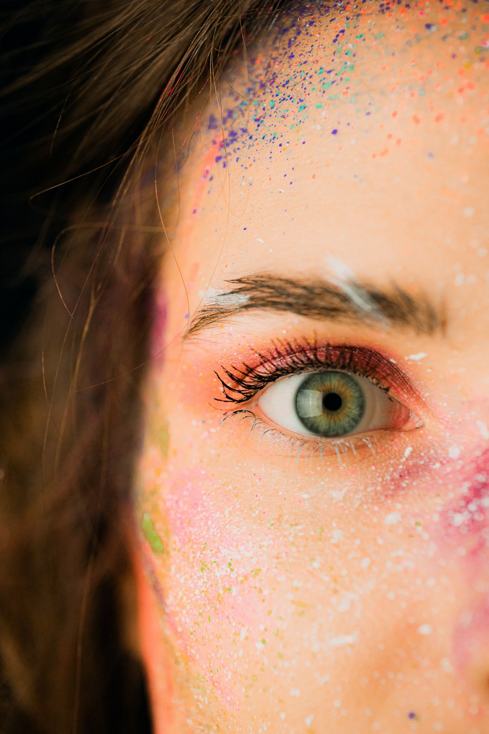 um close up do rosto de uma mulher com pó colorido em todo o rosto