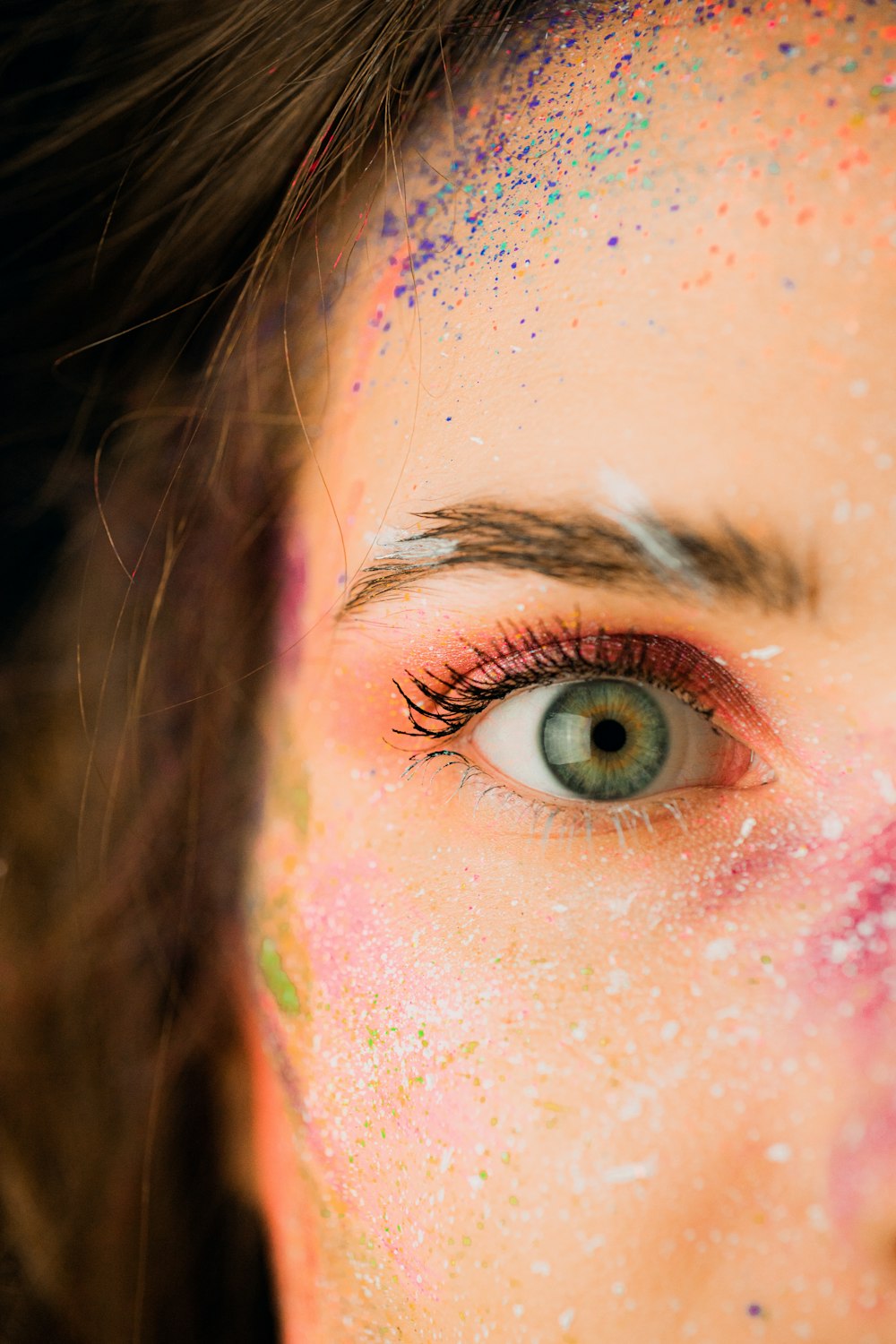 a close up of a woman's face with colored powder all over her face