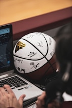 A close-up of a person typing on a laptop with sports memorabilia around.
