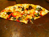Vibrant toppings on a hand-tossed pizza with olives, mushrooms, and peppers in bright lighting.