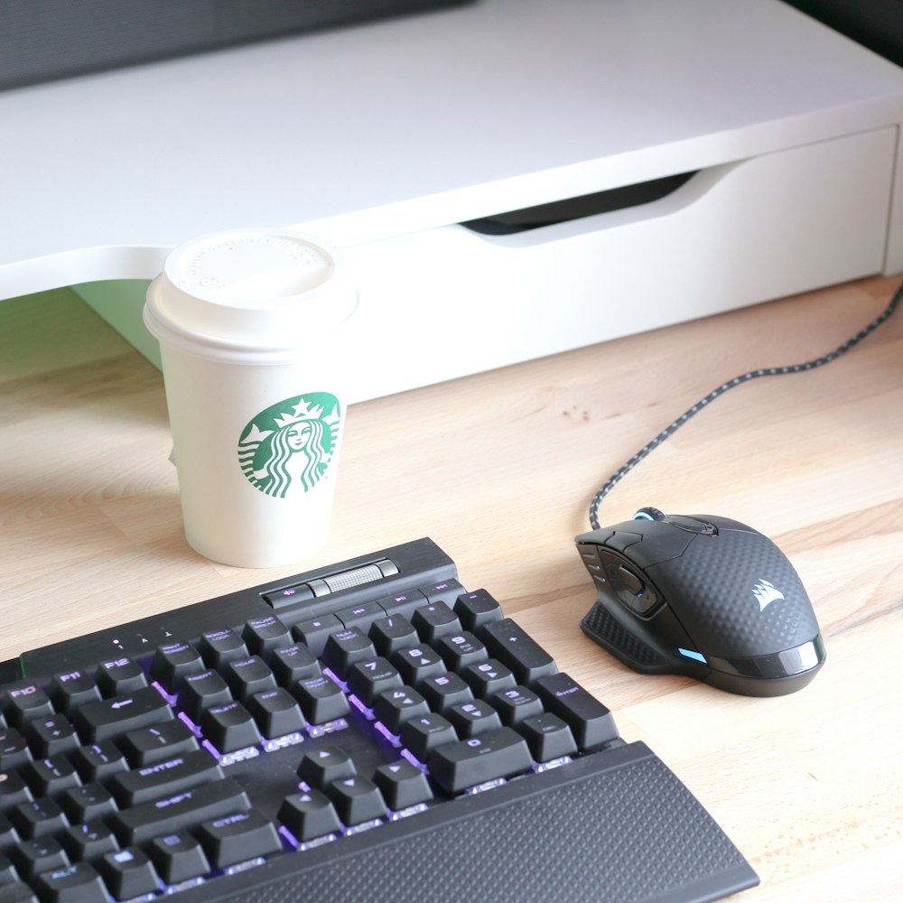 black computer keyboard beside white and green disposable cup