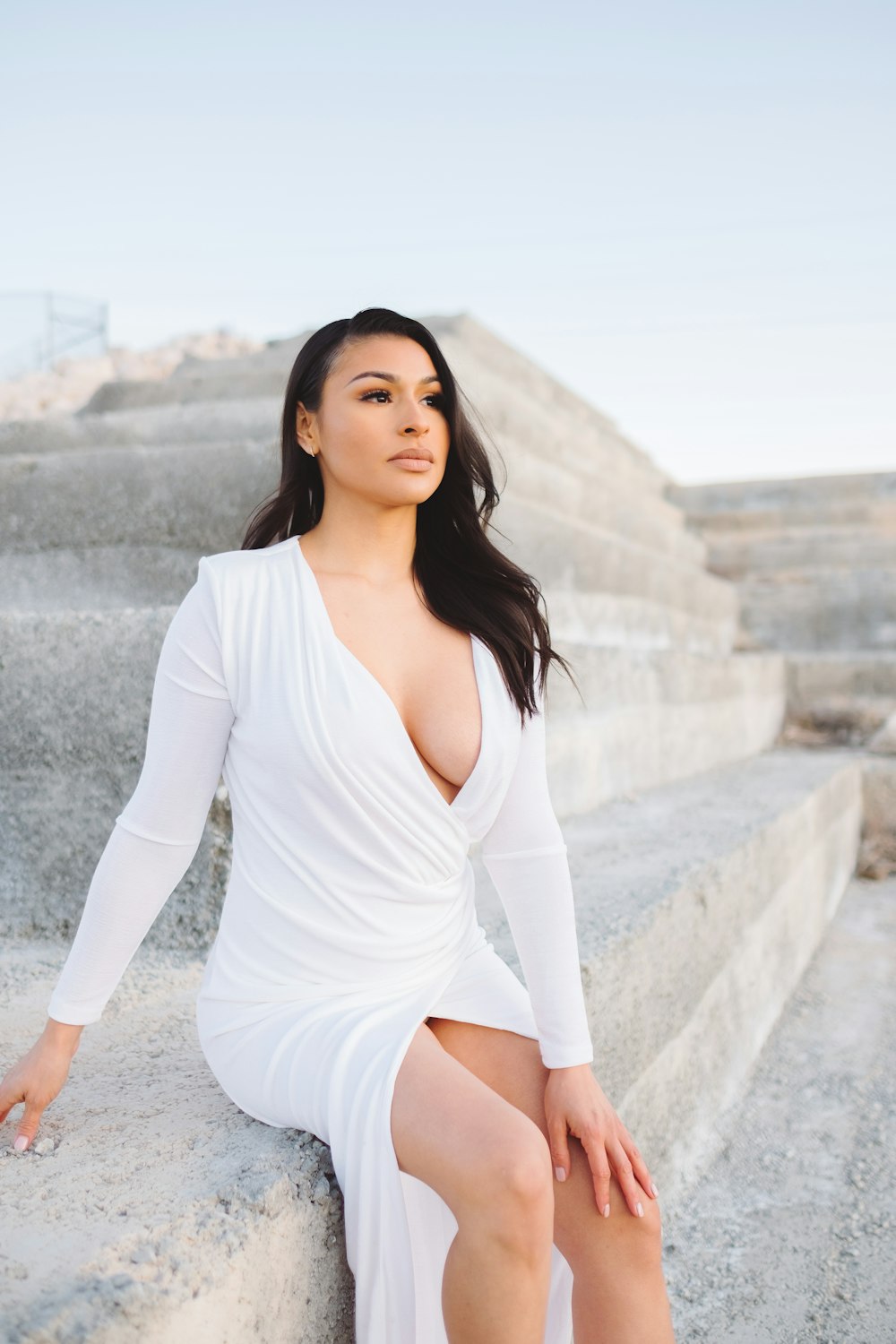 a woman in a white dress sitting on some steps