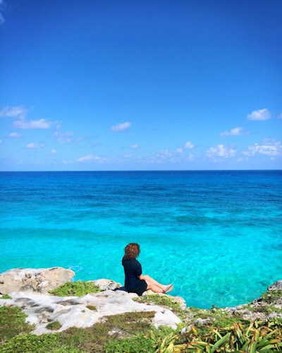 a person sitting on a rock near the ocean
