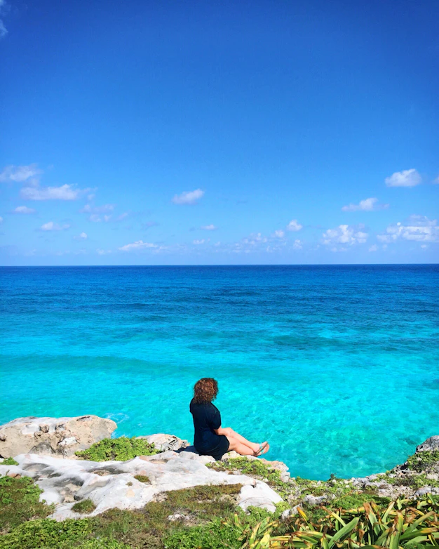 a person sitting on a rock near the ocean