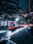 a red and white train traveling through a city at night