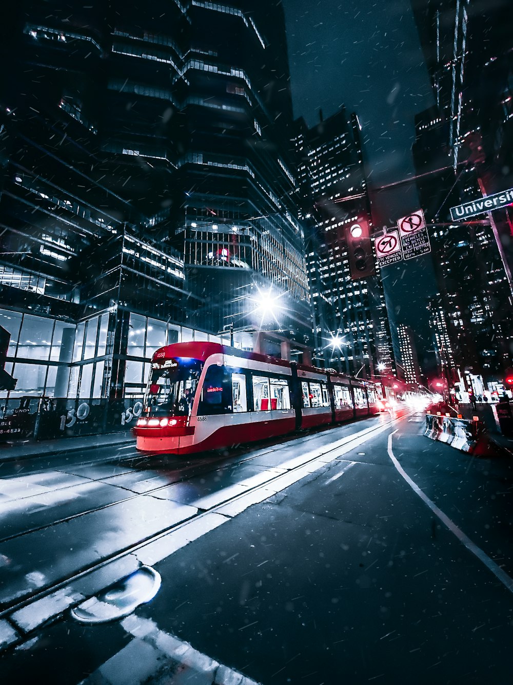 a red and white train traveling through a city at night