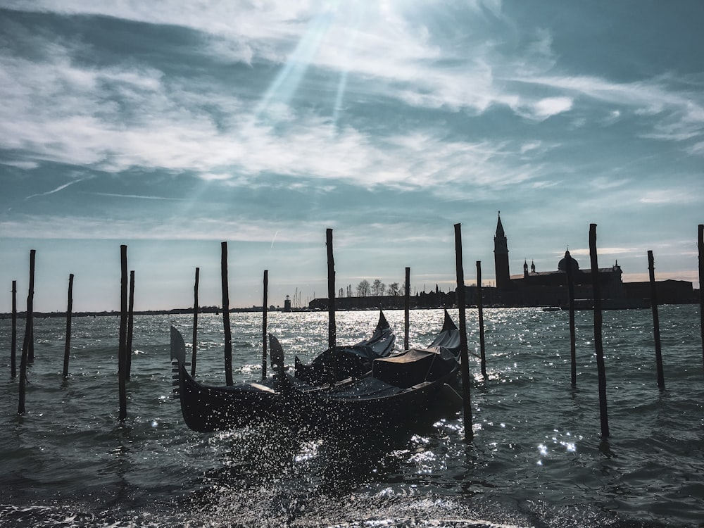 black boat on sea under blue sky and white clouds during daytime