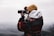person in gray hoodie using black binoculars