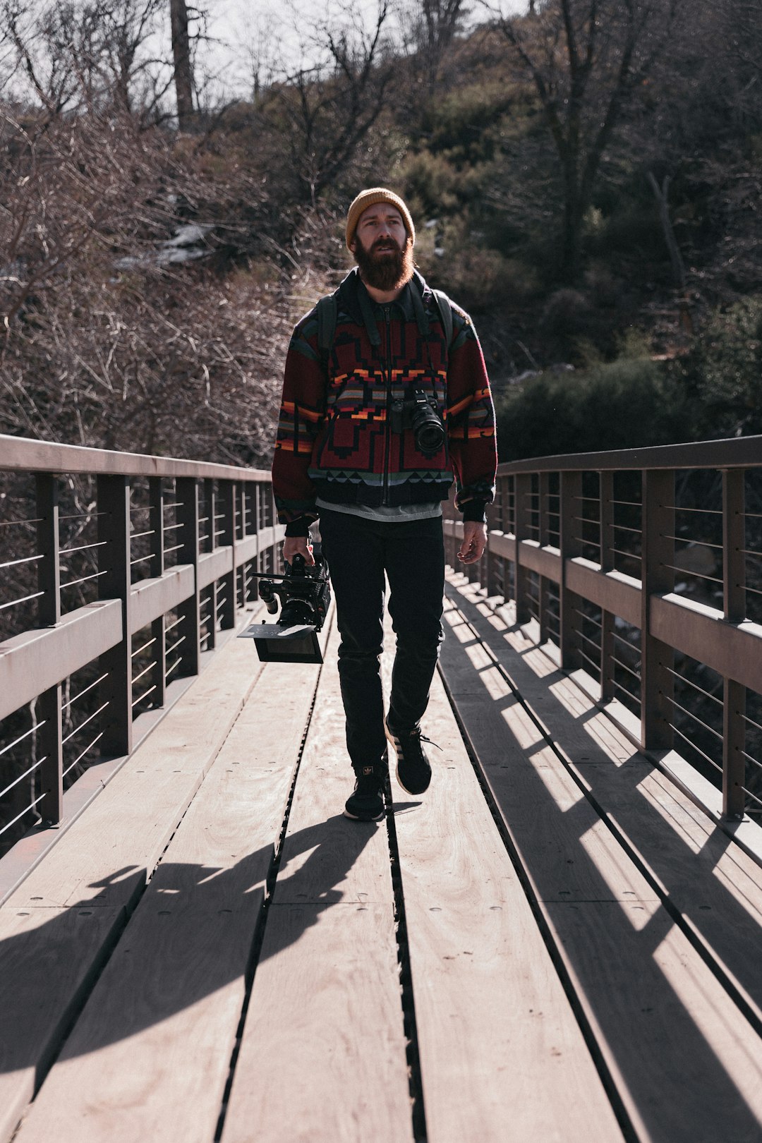 man in red and black jacket and black pants standing on bridge