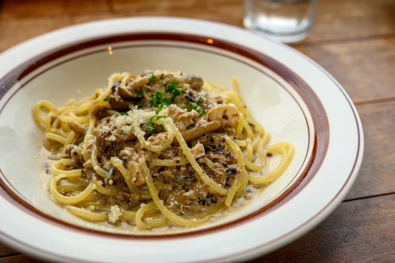 A warm plate of creamy mushroom pasta garnished with fresh herbs.