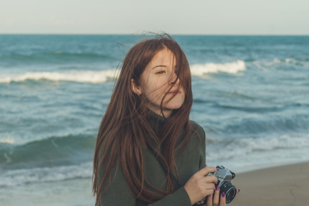 woman in brown turtleneck sweater holding black dslr camera