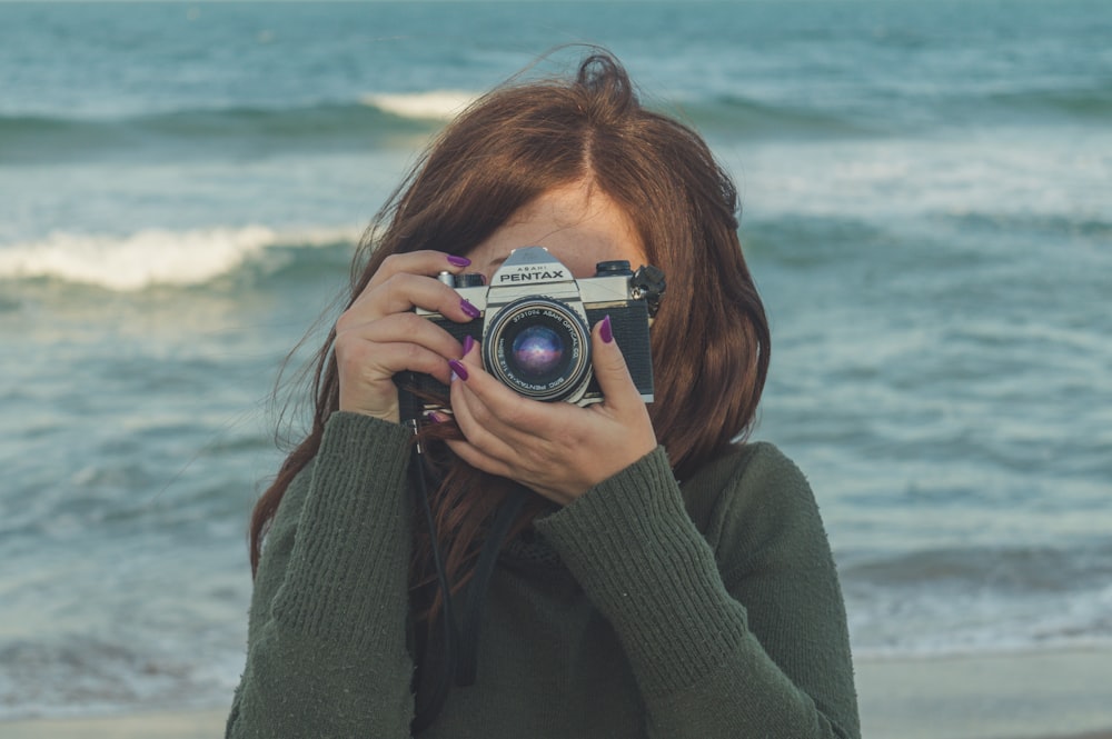 woman in gray sweater holding camera