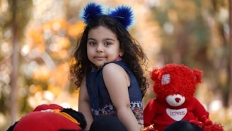 A toddler wearing a cute outfit playing with a soft plush animal on a sunny day.