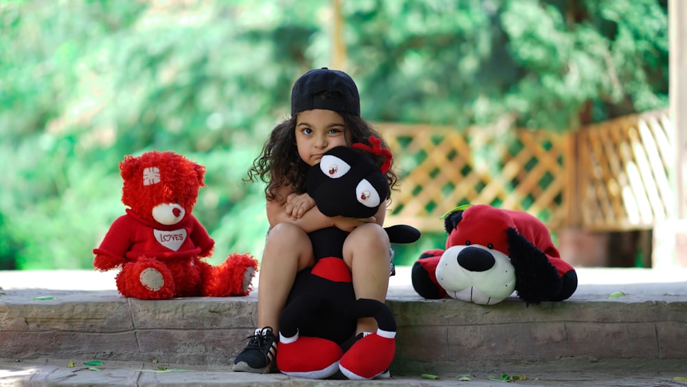 woman in black shorts sitting beside red bear plush toy
