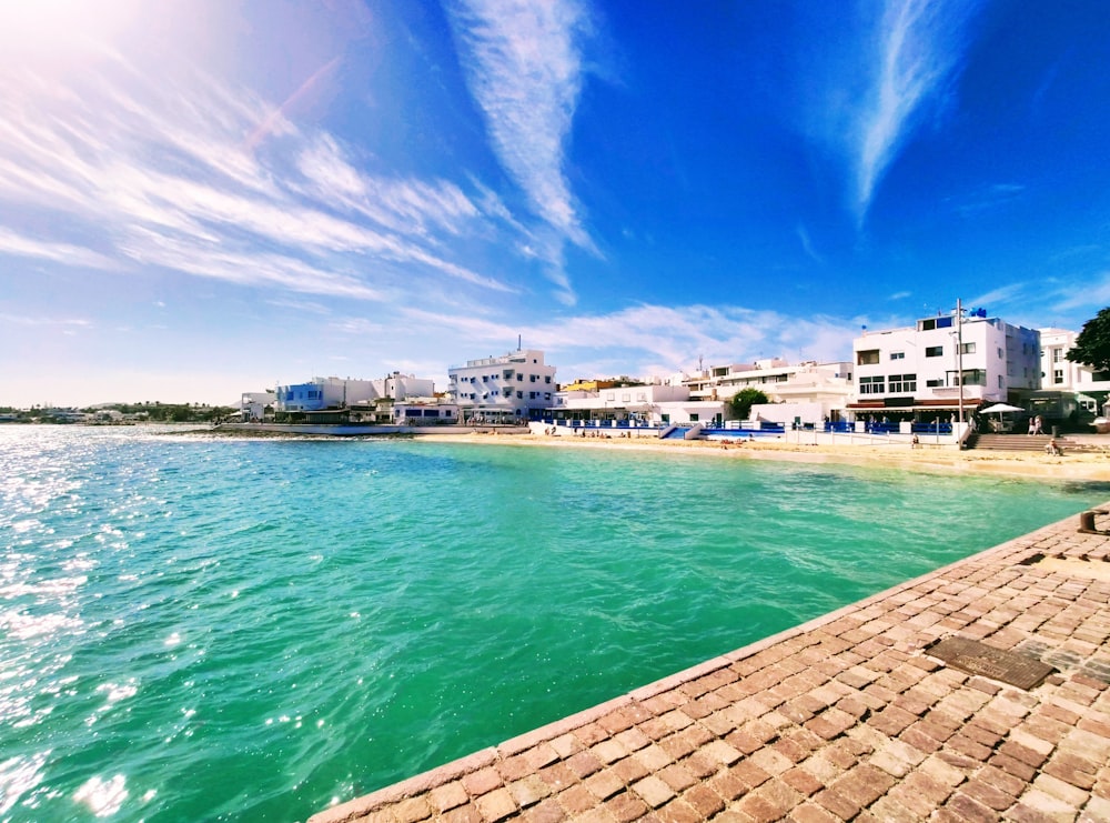 white and brown concrete building beside body of water under blue sky during daytime