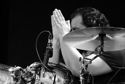 Black and white photo of musician smiling while holding drumsticks.