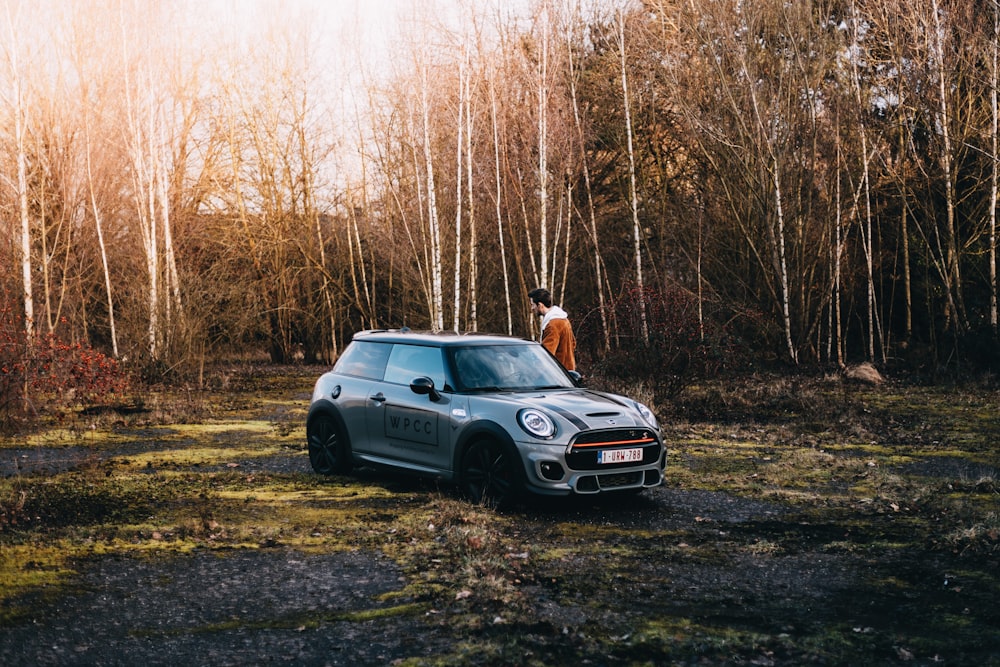 Un hombre parado junto a un coche en un bosque