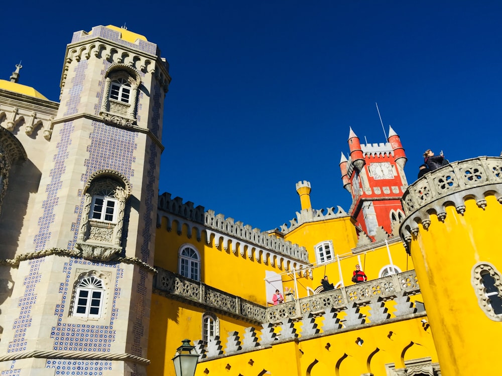 a large yellow castle with a clock on it's side