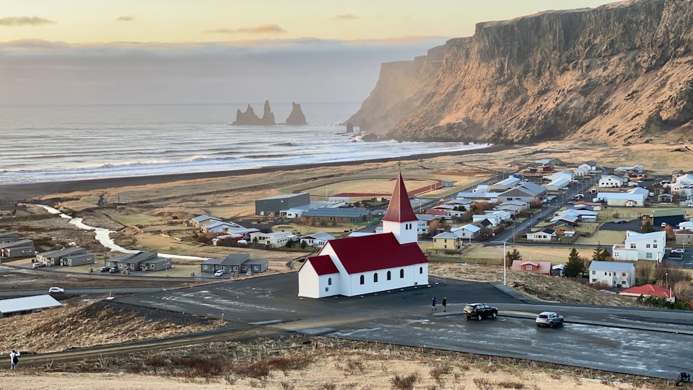 a small white church with a red roof near the ocean