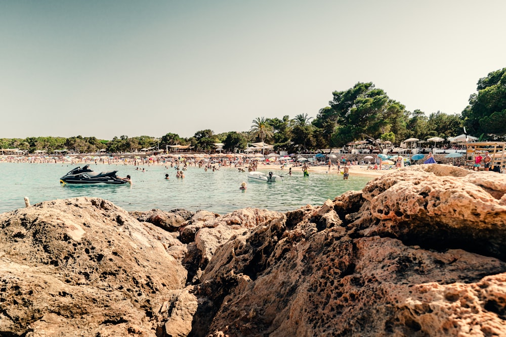 a beach filled with lots of people and a boat in the water