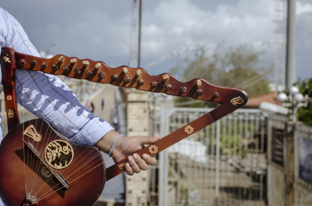 a man is holding a guitar with a leather strap