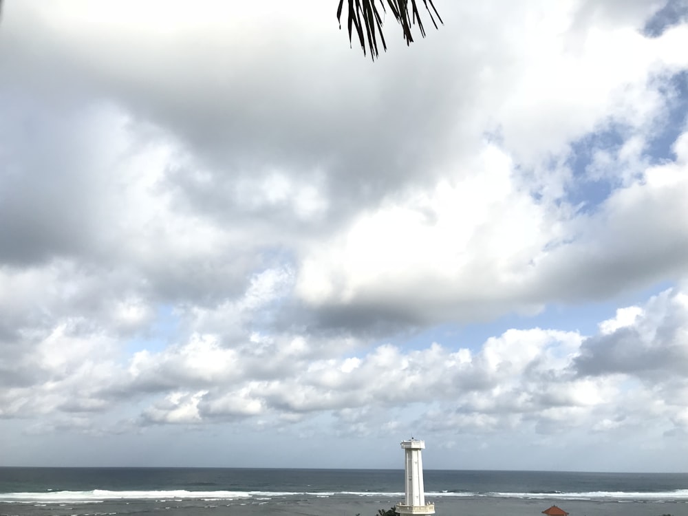 white lighthouse under cloudy sky during daytime