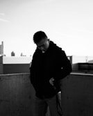 A mysterious figure in a leather jacket standing on a rooftop overlooking a city skyline at midnight.