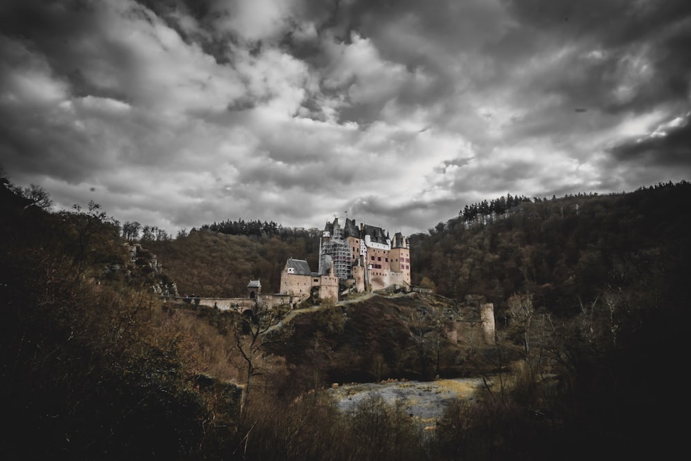 a castle on top of a hill under a cloudy sky