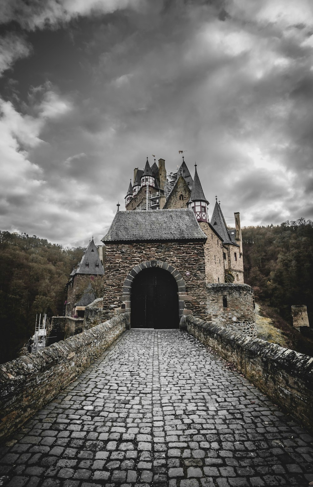 a stone walkway leading to a castle under a cloudy sky