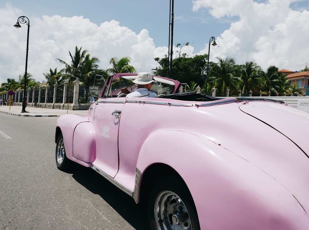 a pink convertible car parked on the side of the road