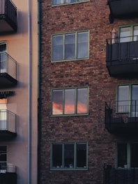A city apartment building with balconies and bright windows at sunset