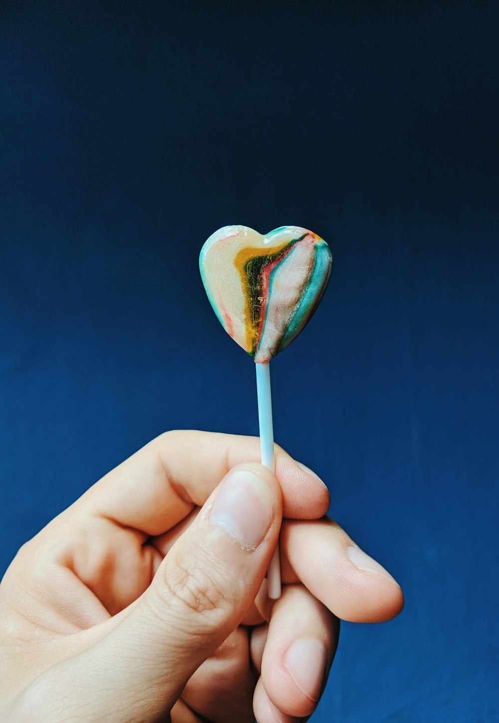 person holding white and pink lollipop